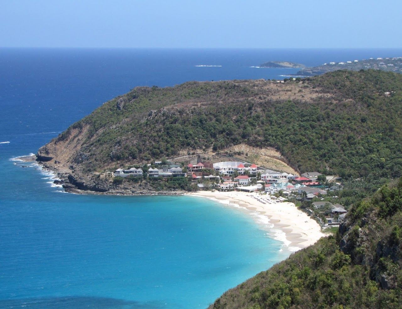 The broad pale sand and open water of Anse des Flamands with green slopes behind on St Barths