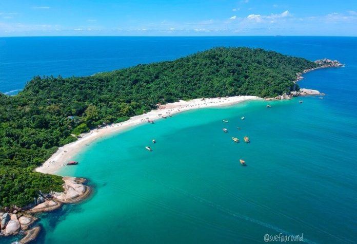 The long fine sand of Praia do Campeche in Florianopolis with Atlantic surf and the protected island offshore