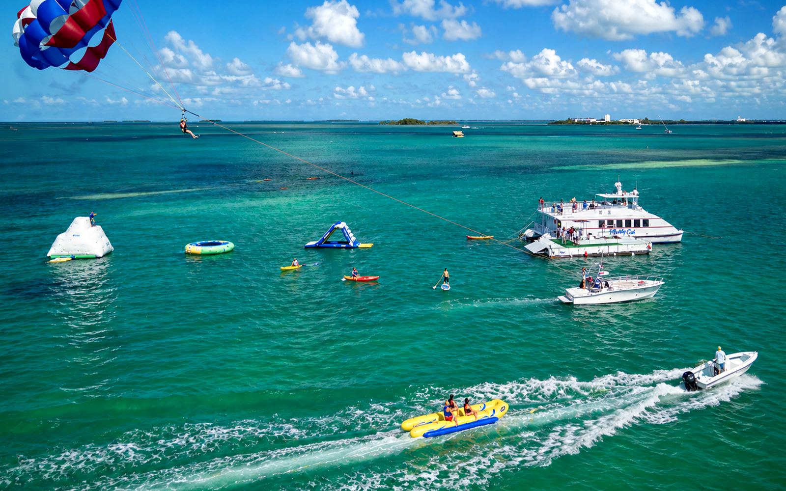 Kiteboarders and paddlers on the flat shallow water off a Florida Keys beach near Key West