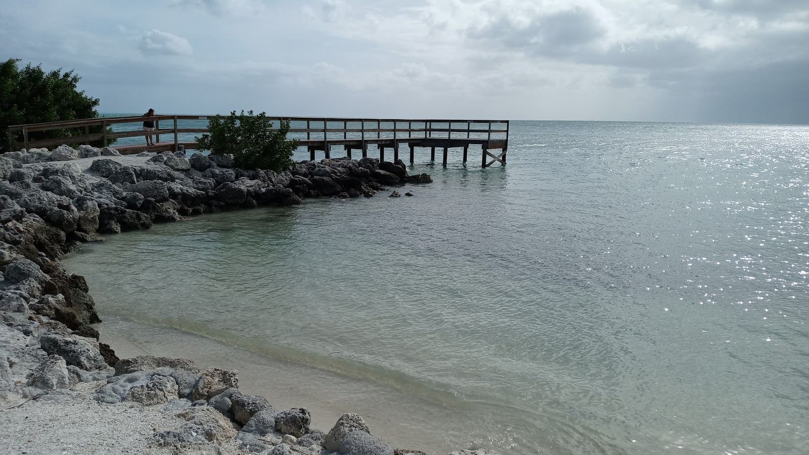 A Florida Keys beach and clear shallow water under a warm sky along the island chain