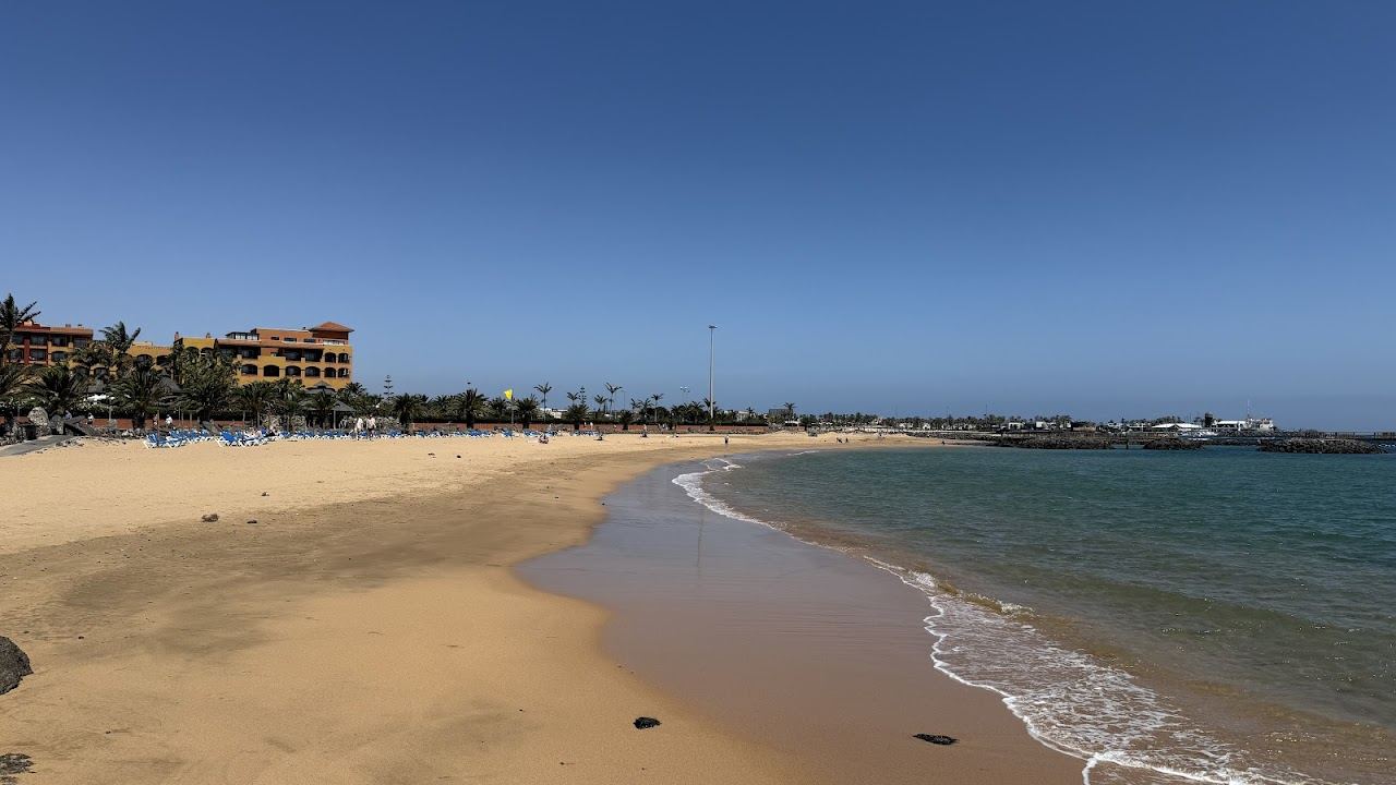 Calm shallow turquoise water and golden sand on a sheltered family beach in Fuerteventura