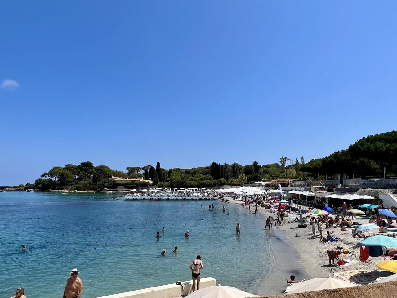 Sheltered sandy crescent and clear calm water at Plage de la Garoupe on Cap d'Antibes France