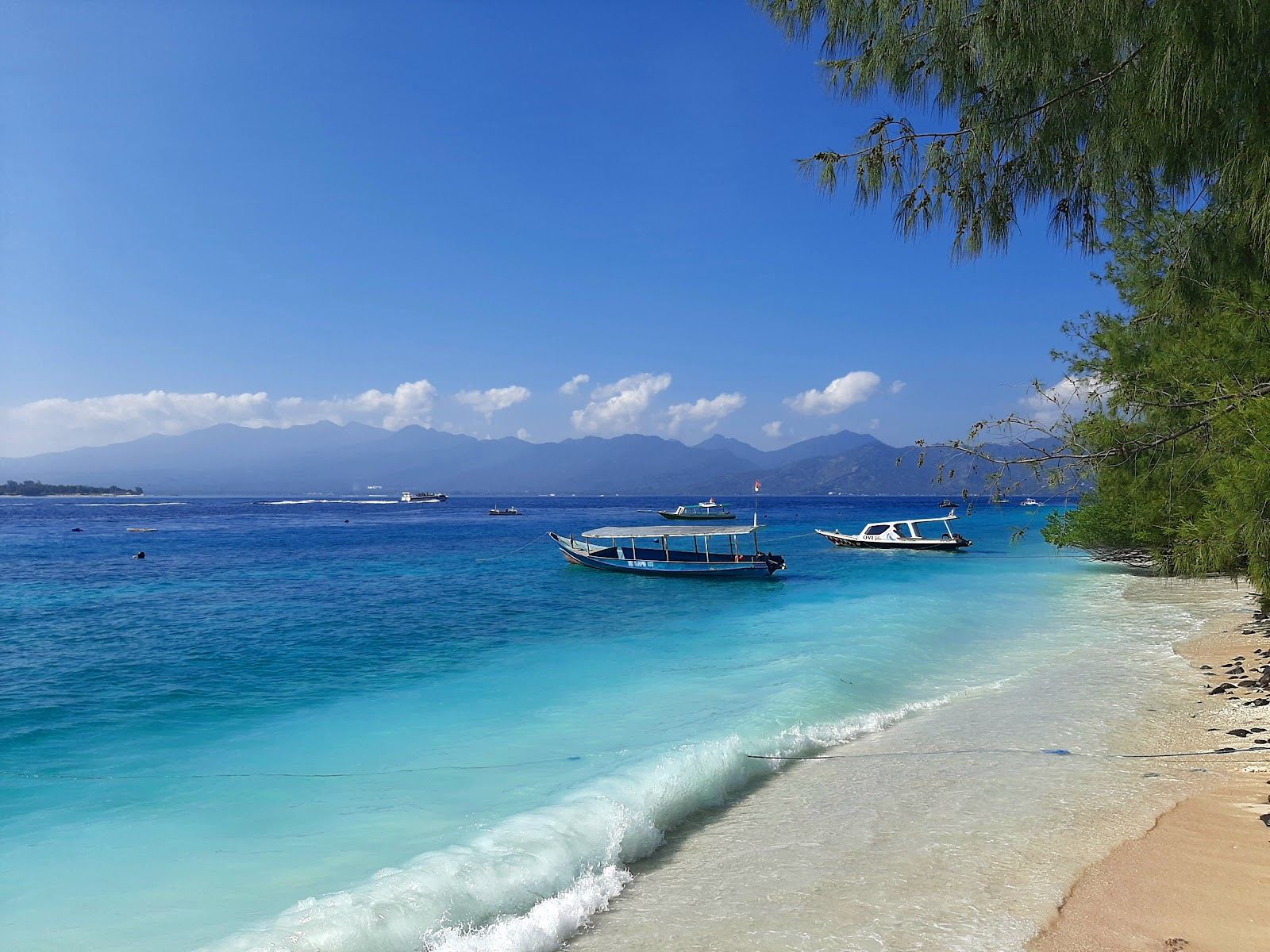 Soft white coral sand and clear turquoise water on a quiet Gili Islands shore near Lombok, Indonesia