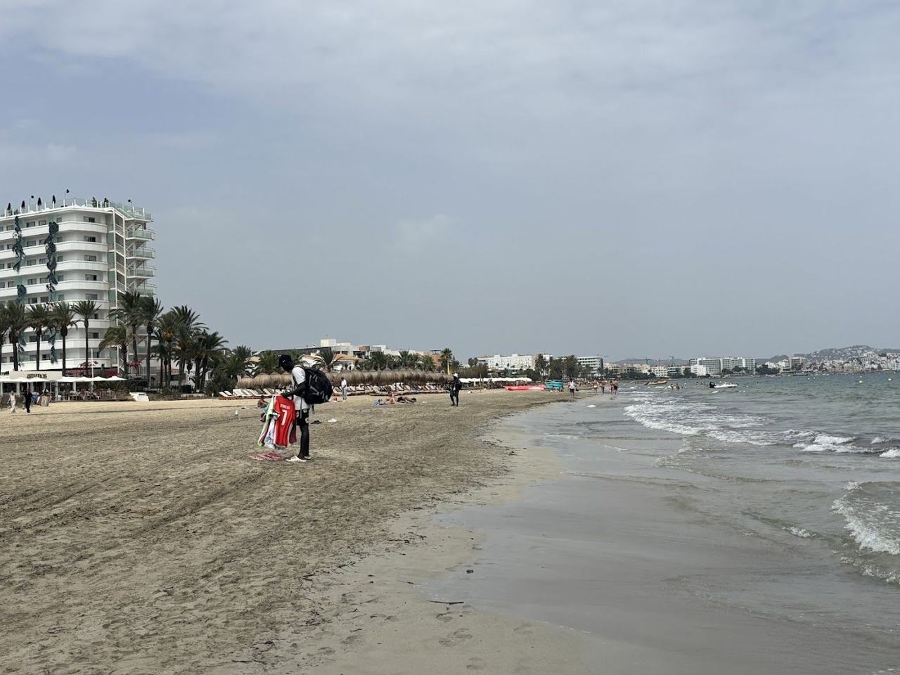 A lively beach lined with clubs and daybeds where groups gather by the sea in Ibiza