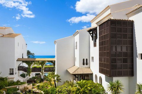 A large villa with a pool above golden cliffs and a sandy cove on the Algarve
