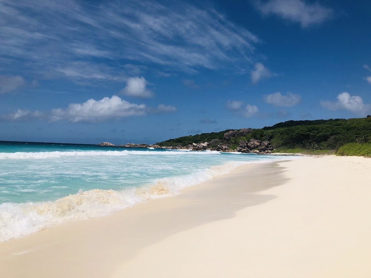 Wide white sand beach, rolling surf and granite hills at Grand Anse on La Digue in Seychelles