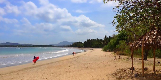 Surfers and clean waves rolling into a golden Guanacaste beach