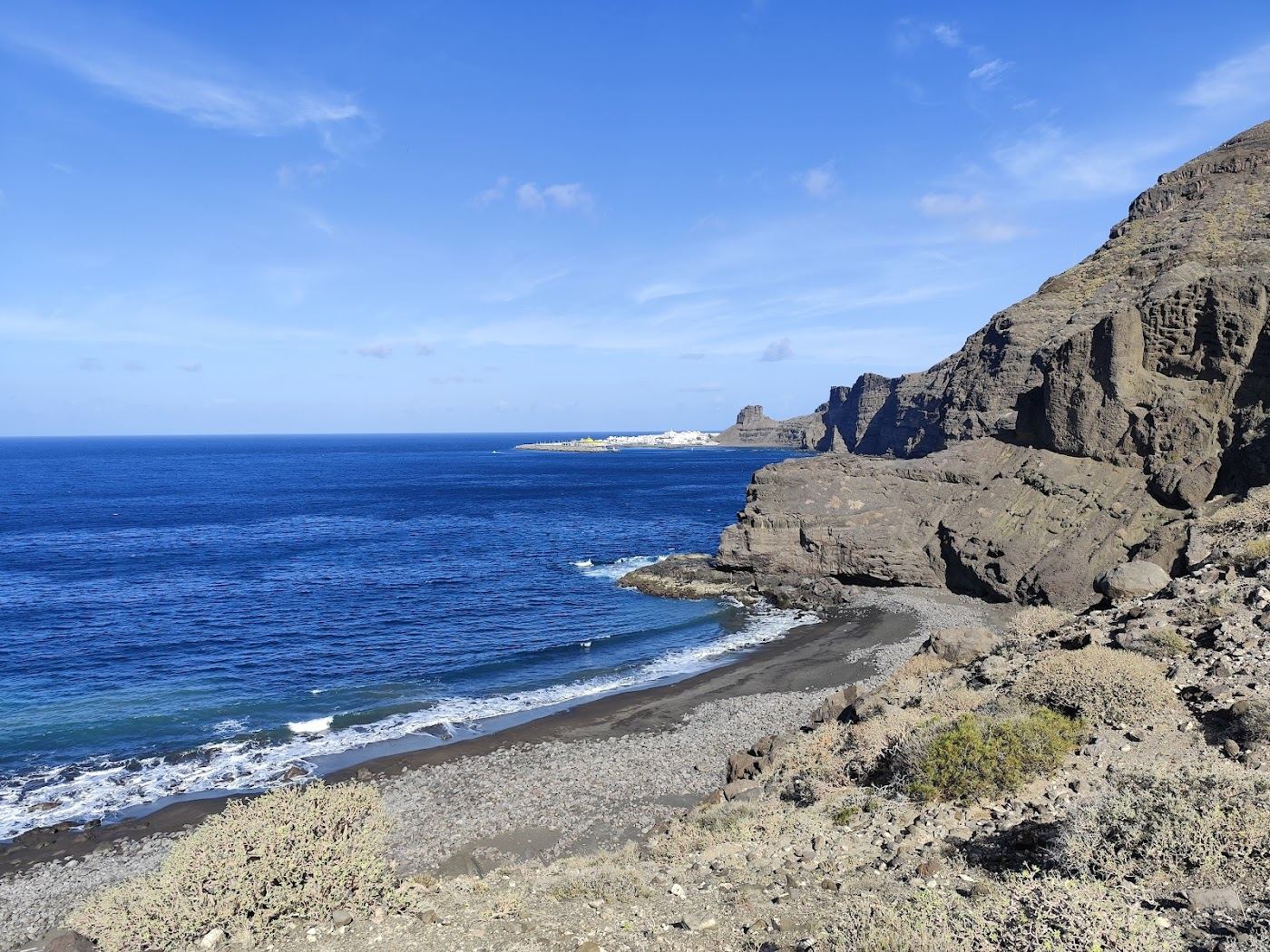 Wild unspoilt cove of sand and pebble below pine clad slopes at Guayedra in north west Gran Canaria