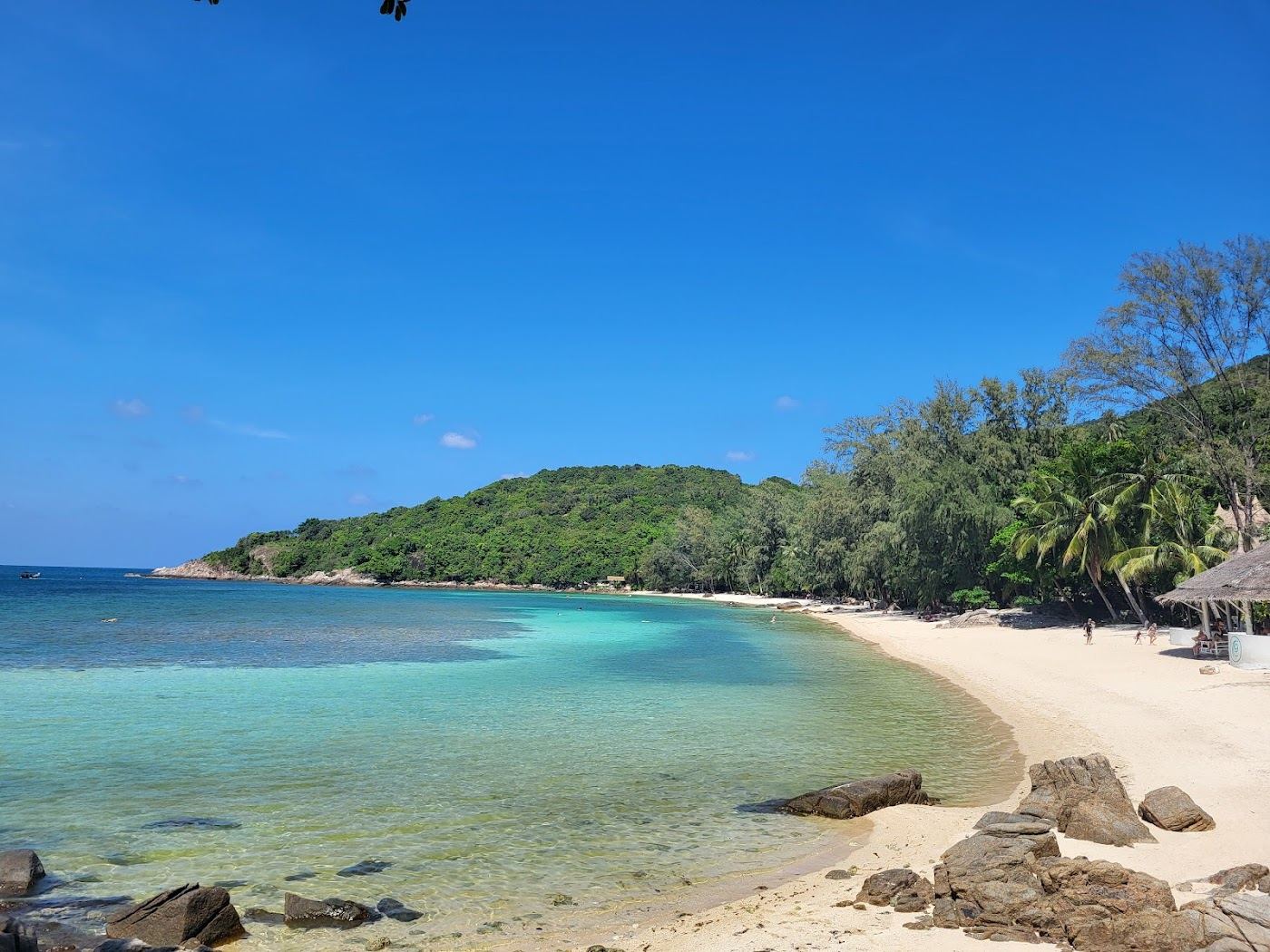 The calm clear water and jungle backed sand of the coral cove at Haad Khom on Koh Phangan