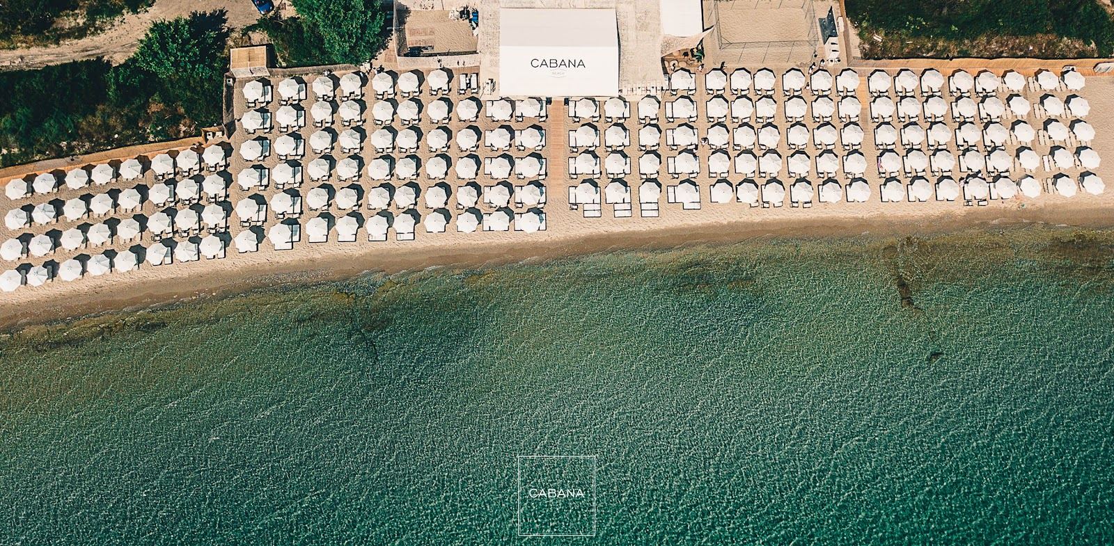 Luxury sunbeds on a long sandy beach above turquoise water at a Halkidiki beach club