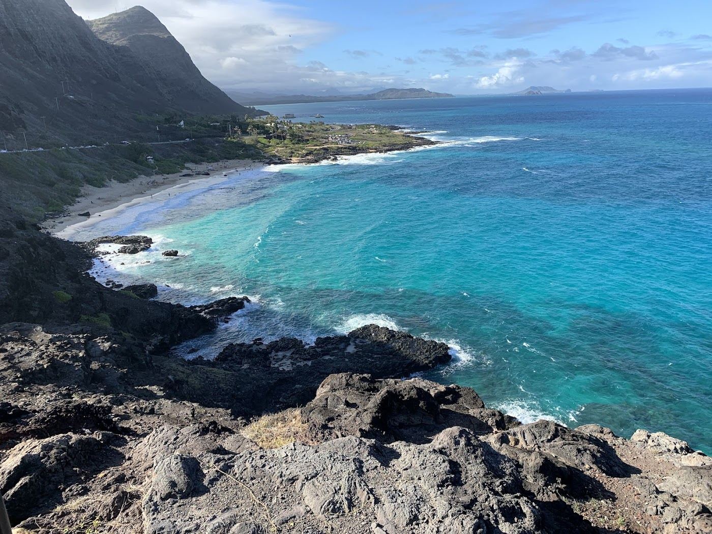 The bright sand cove of Makapuu Beach under the lighthouse headland at the east tip of Oahu