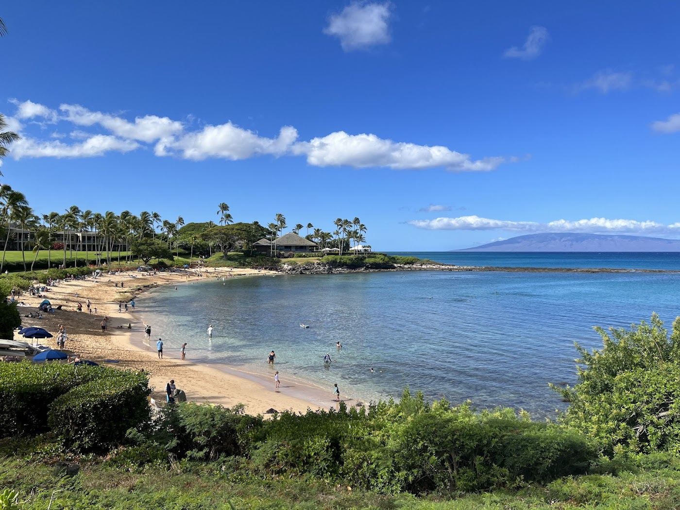 The sheltered crescent and calm clear water of Kapalua Bay between two rocky points on Maui