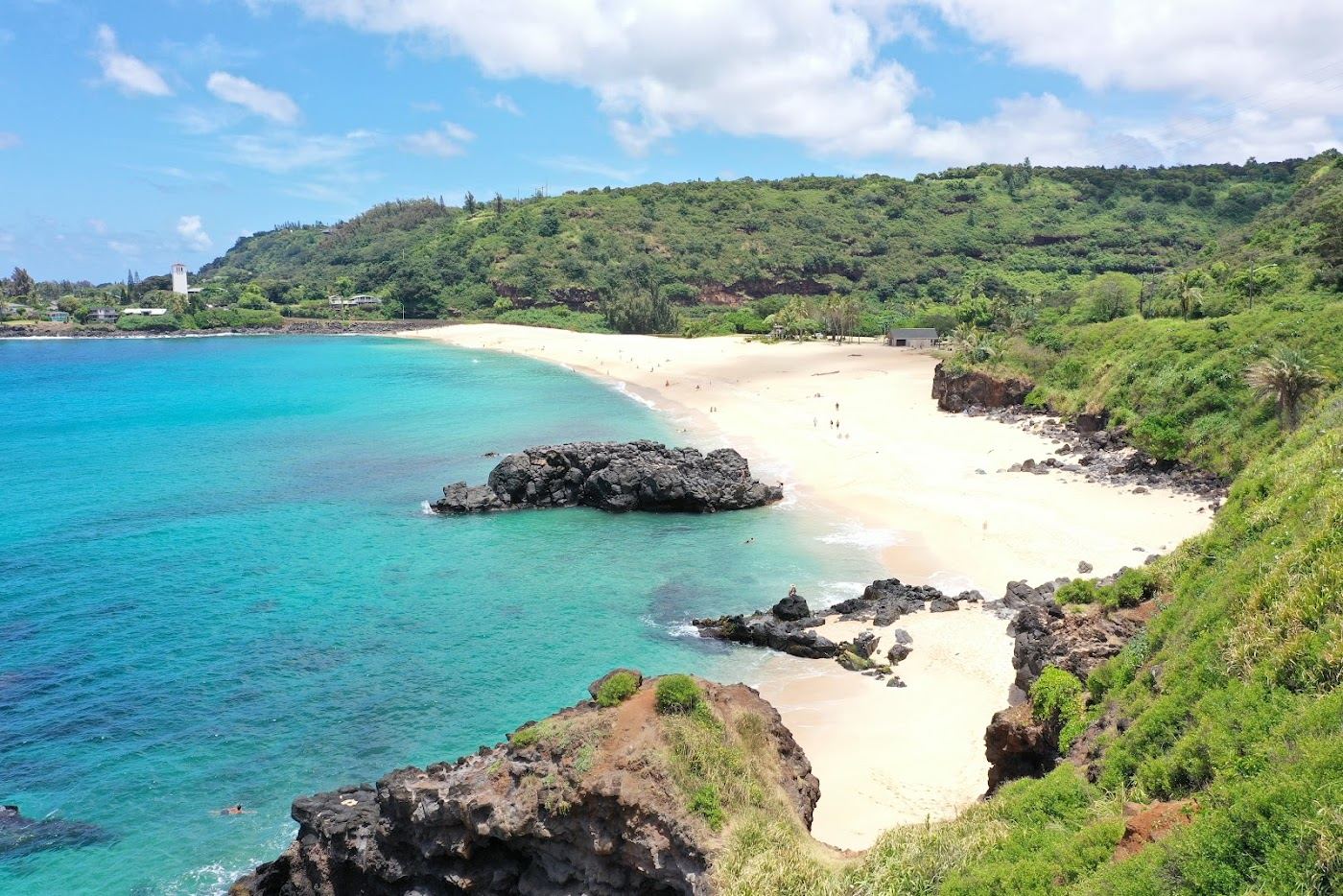 The wide bay and jump rock of Waimea Bay calm in summer on the North Shore of Oahu