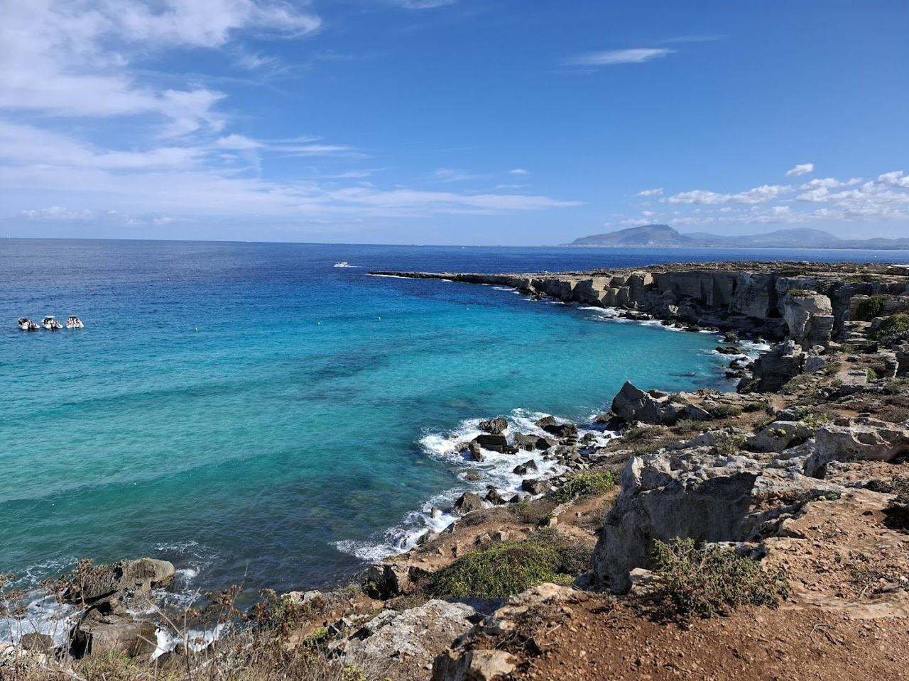 A former quarry turned swimming cove of vivid blue water and pale tufa rock off western Sicily.
