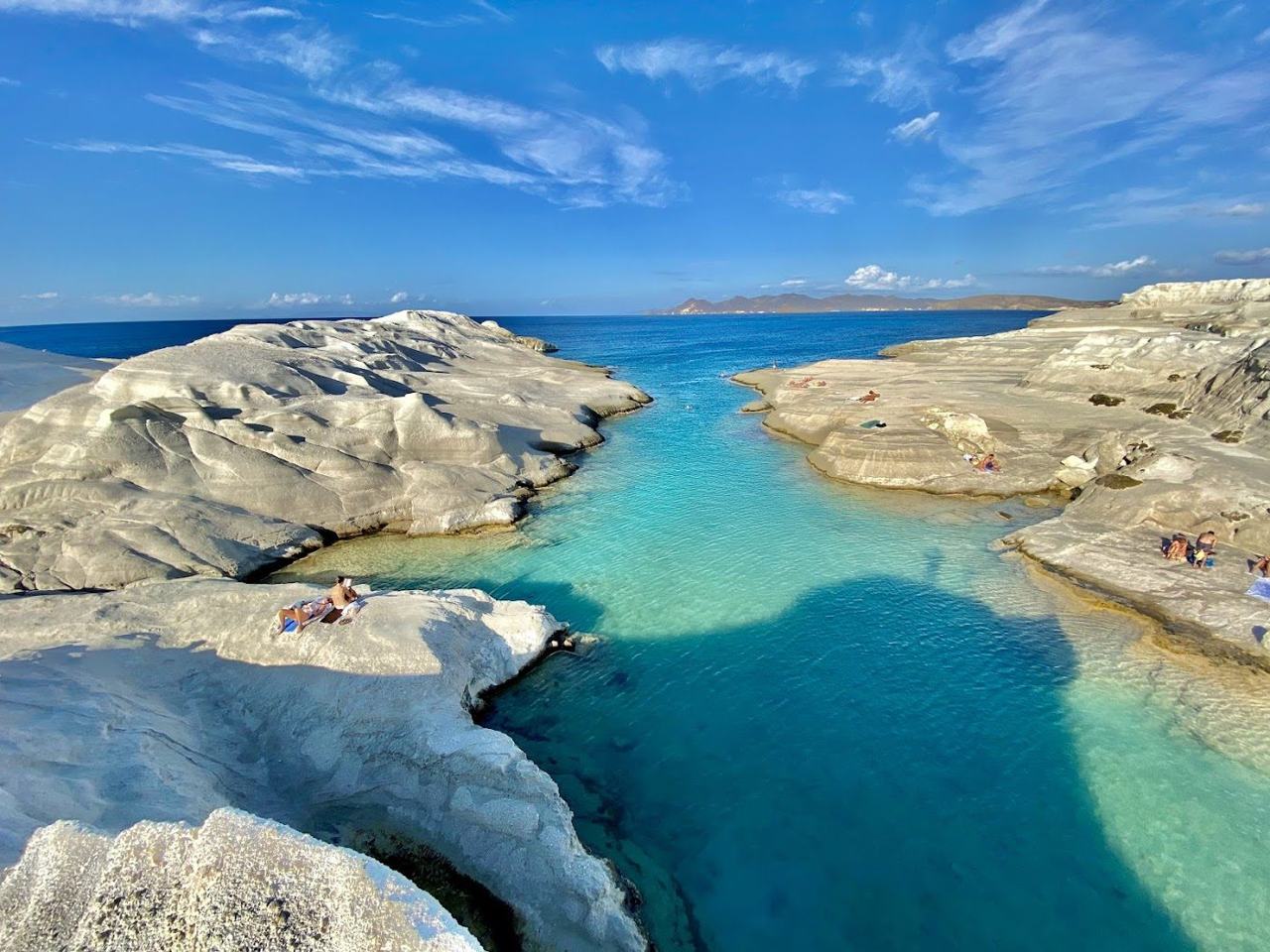 A lunar landscape of white volcanic rock and a small inlet of deep blue water on the Cycladic island of Milos.