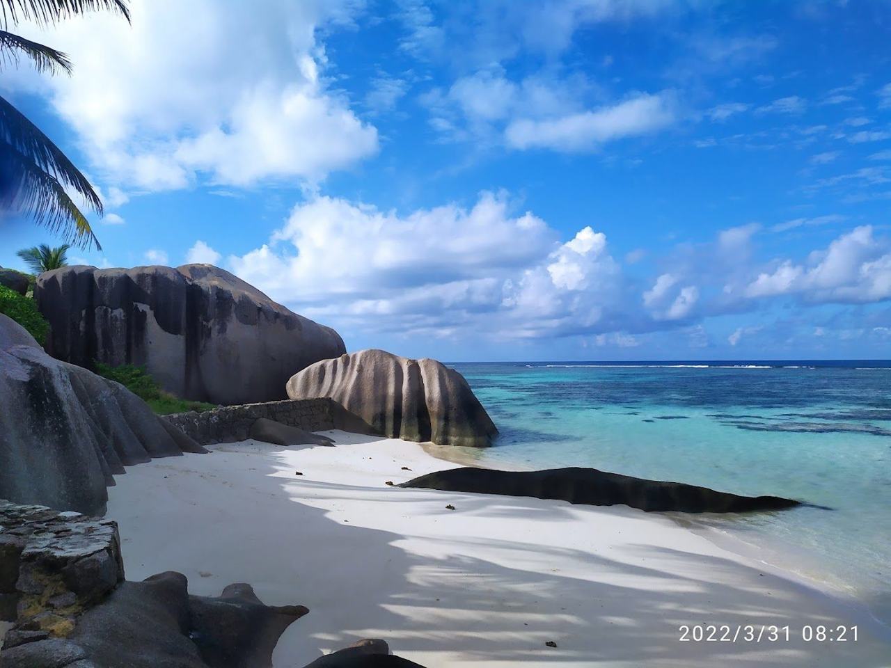 Granite boulders, glowing sand and warm shallow water across a cluster of green islands in the Indian Ocean.