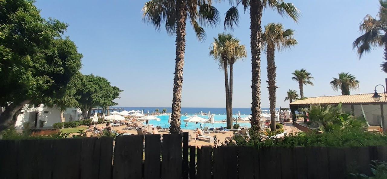 Long shingle shore and deep blue water with kitesurf sails offshore at Ialysos beach near Trianta on the west coast of Rhodes