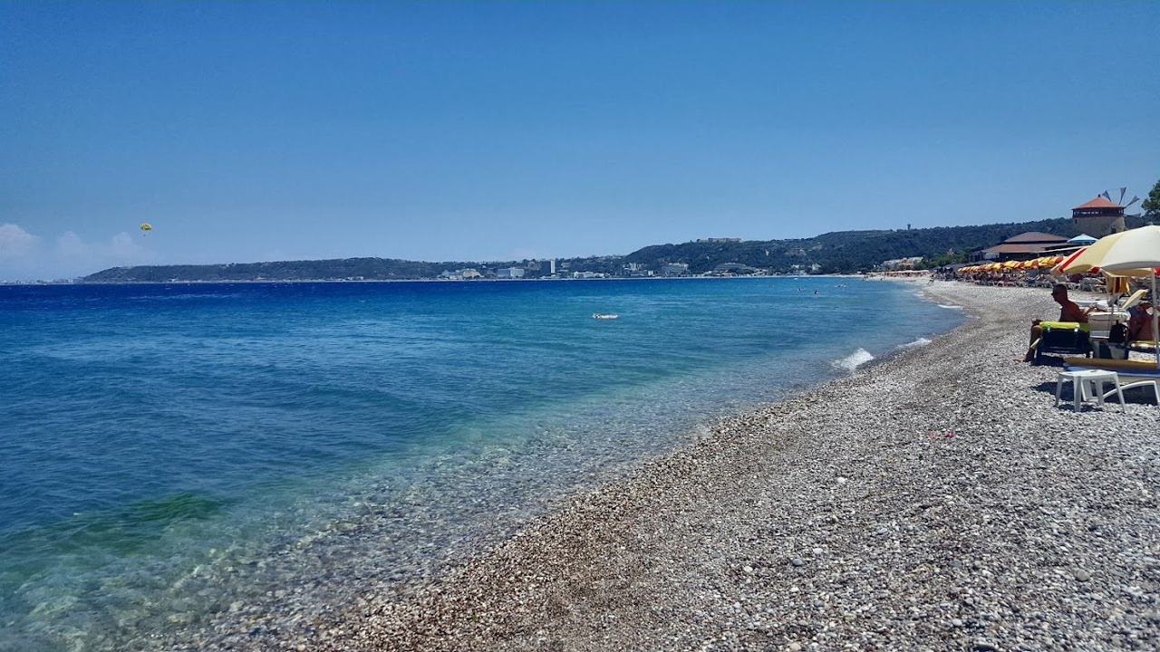 Open shingle shore and clear deep water backed by the town of Trianta at Ialysos beach on the west coast of Rhodes