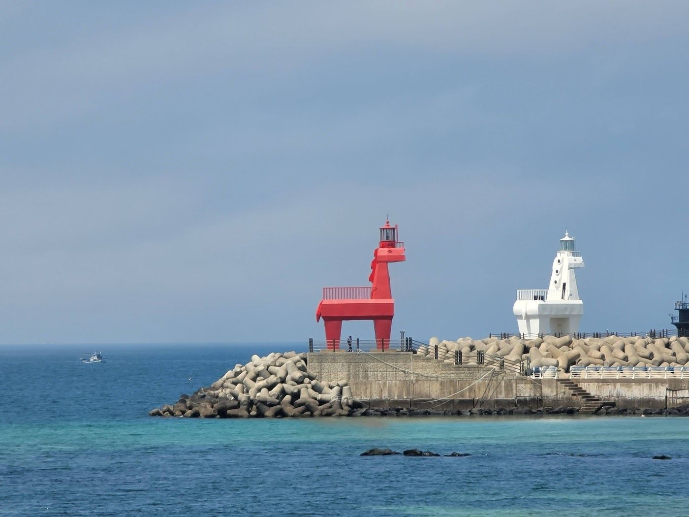 A busy summer beach near Jeju City with the horse shaped lighthouses behind