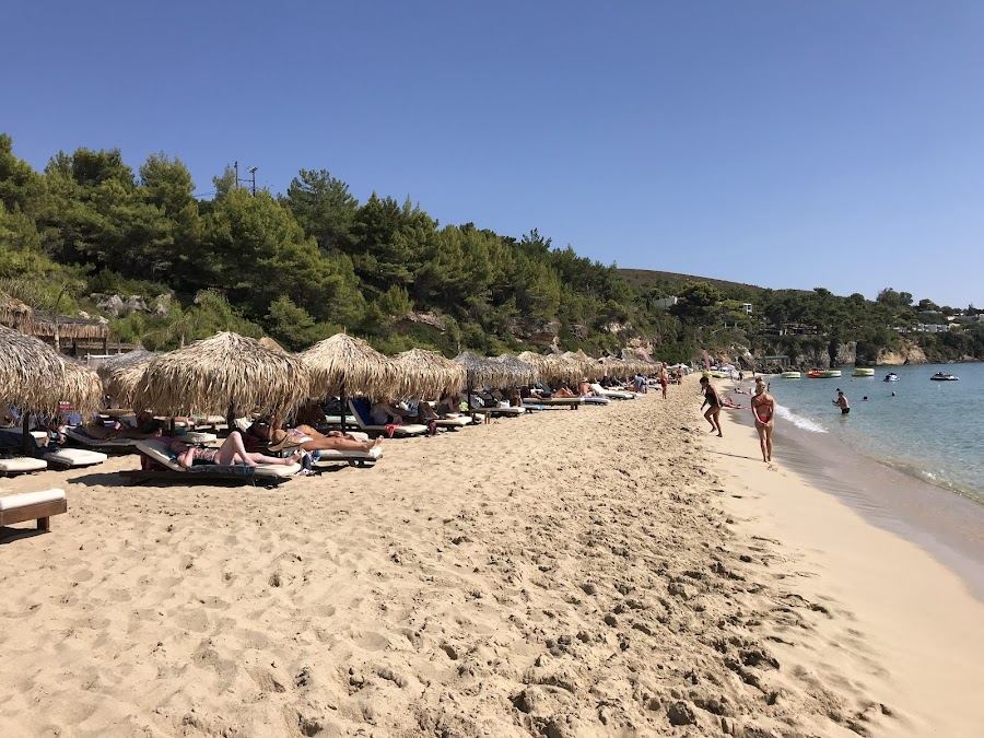 Beach bar and sunbeds beside clear water at Makris Gialos near Lassi in Kefalonia