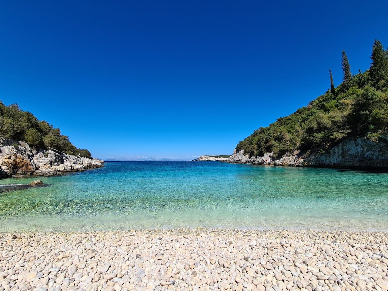 The hidden pebble cove and clear water of Dafnoudi Beach reached by a forest path near Fiskardo in Kefalonia