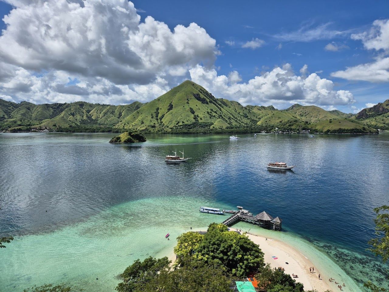 Small sand beach below a green hill at Kelor Island near Labuan Bajo