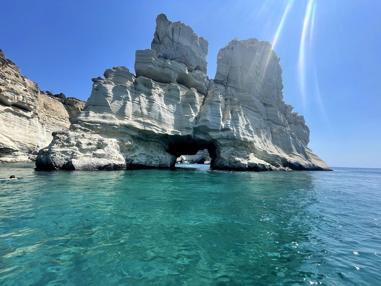 White rock arches and caves at Kleftiko reflected in clear blue water with no beach club on the southwest coast of Milos
