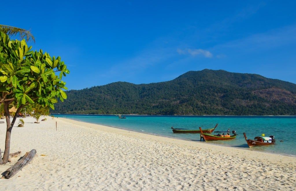 Longtail boats on the clear water of Sunrise Beach on Koh Lipe in the Tarutao marine park