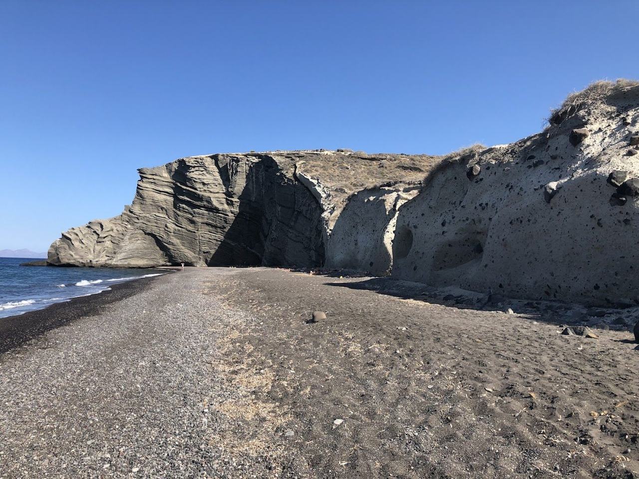 The remote dark sand and high cliffs of Koloumbos Beach in northeast Santorini