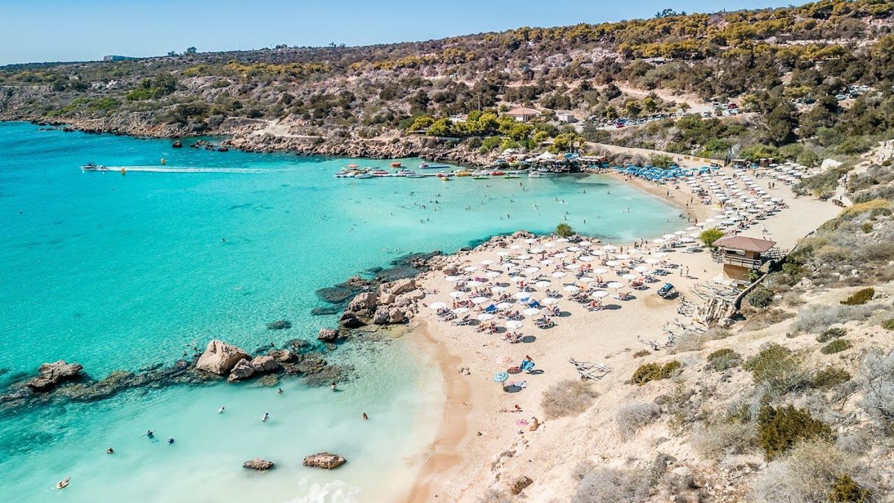 Sheltered cove of soft sand and clear turquoise water backed by pine clad hills at Konnos Bay near Cape Greco Cyprus