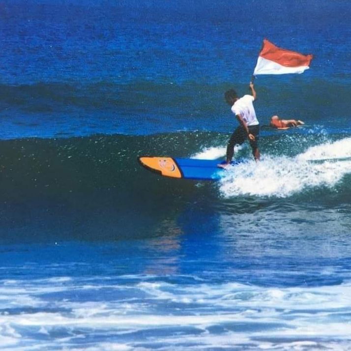 Long golden sweep of Kuta Beach in Bali with surfers at sunset
