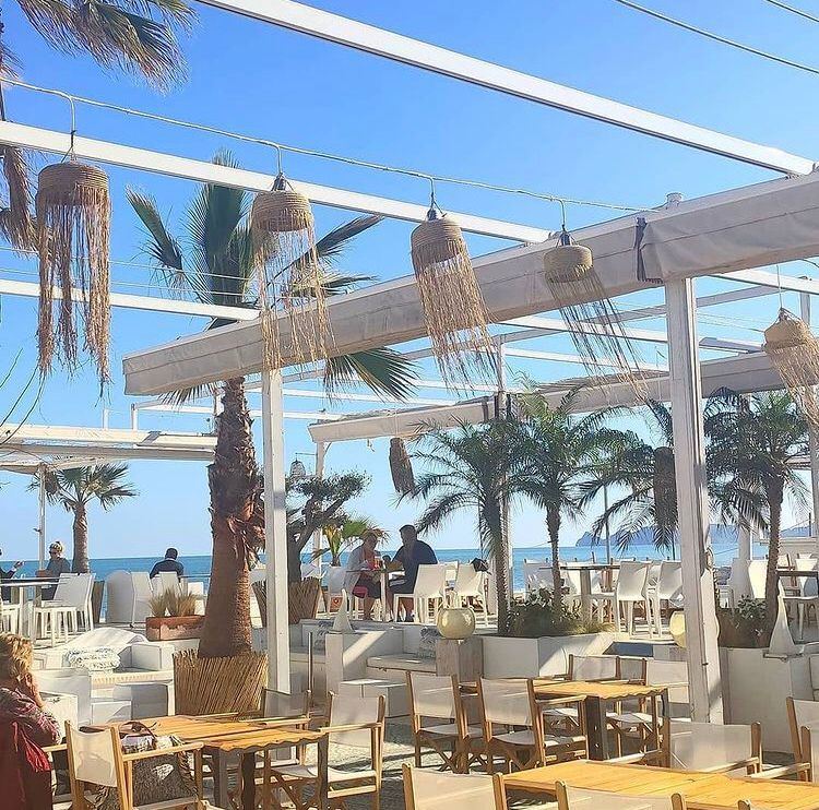 Balinese beds and parasols on the rock shore at La Siesta beach club in Javea