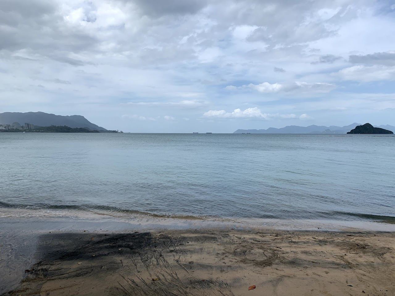 Mineral darkened sand and fishing boats at Black Sand Beach on the north coast of Langkawi