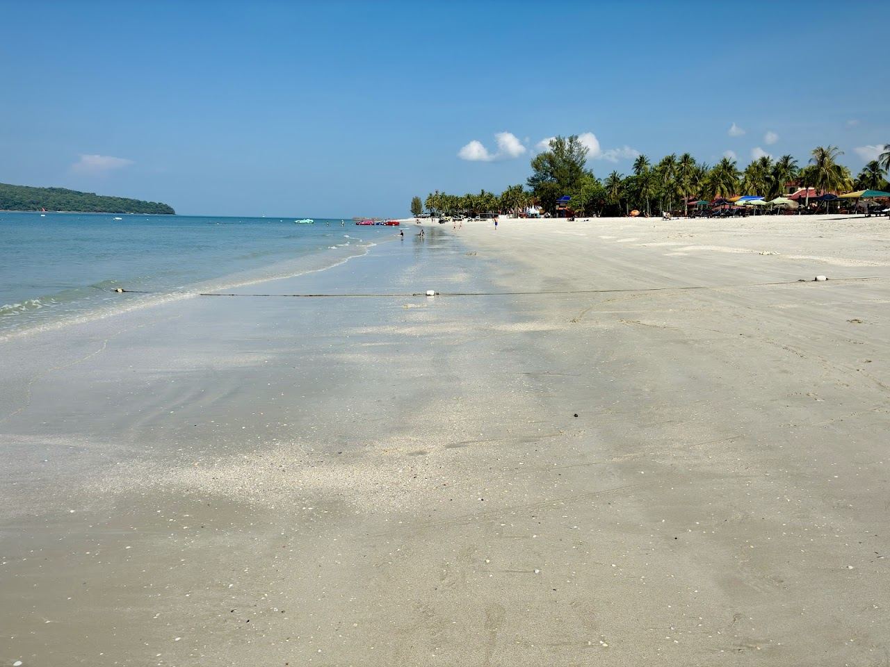 The long sandy strip of Pantai Cenang at dusk backed by the beach bars and nightlife of Langkawi