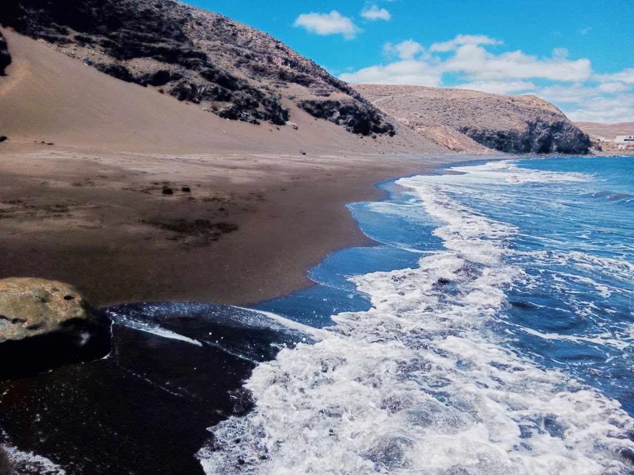 Quiet wild cove with dark sand and calm water away from the resorts in Lanzarote