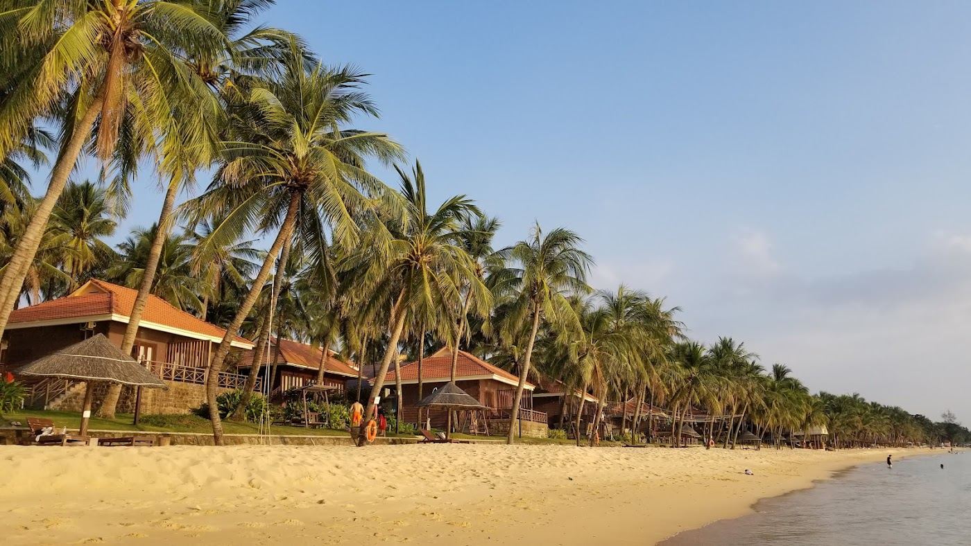 Long west coast strip of golden sand and calm shallow water at sunset on Long Beach, Bai Truong, in Phu Quoc