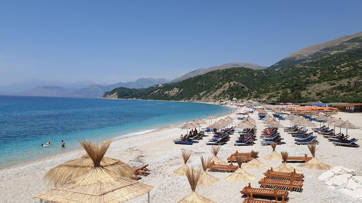 The clear water and pebble shore of Lukove beach below the olive hills of the southern Albanian Riviera