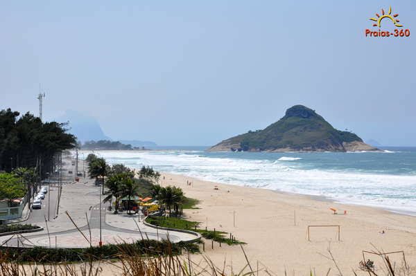 Surfers in the water at Macumba Beach with the headland behind in the west of Rio de Janeiro