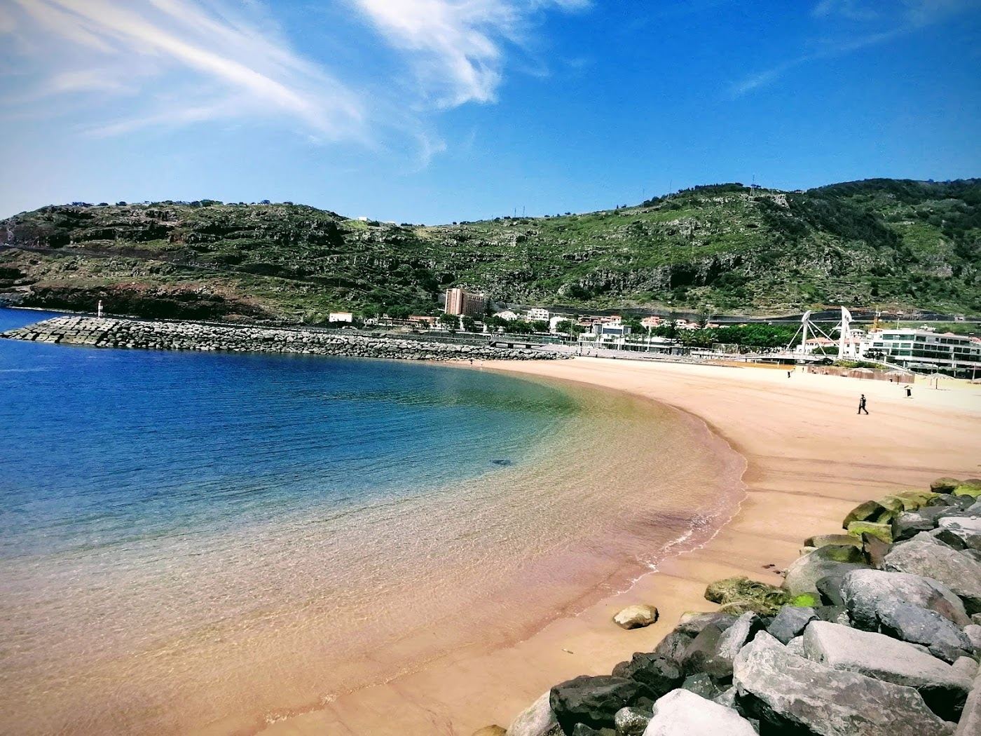 Calm sheltered golden sand bay between two piers at Machico on the east coast of Madeira