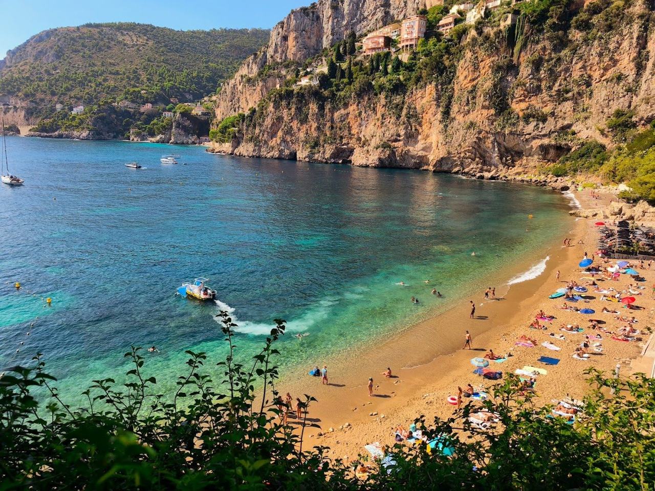 Hidden cove with clear turquoise water and beach clubs at Plage Mala Cap d'Ail near Monaco
