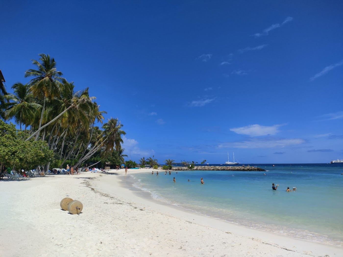 The free public bikini beach with white sand and clear shallow water on Maafushi, the budget local island in the Maldives
