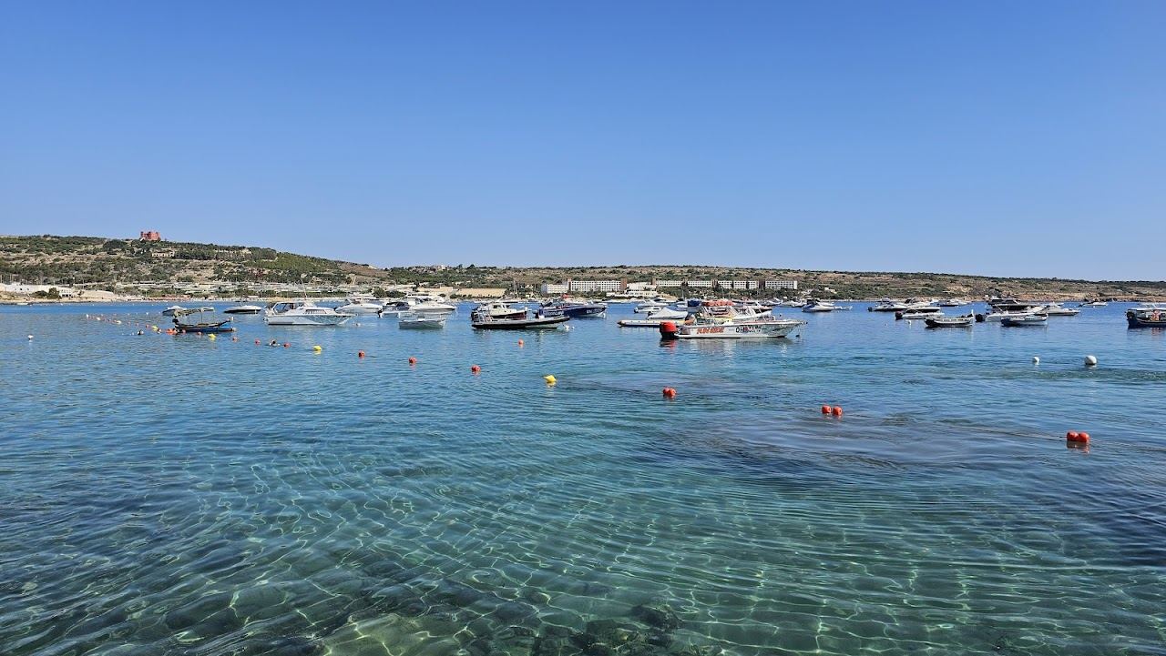 Shallow turquoise water over the long sandy stretch of Mellieha Bay in northern Malta