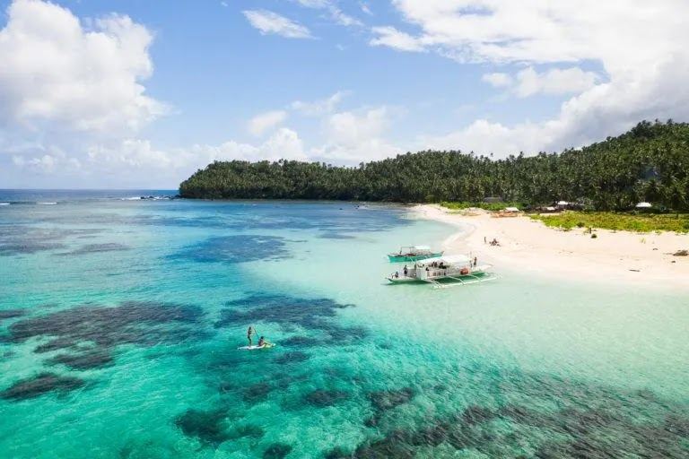 The quiet white sand islet of Mam on Island ringed by clear shallow coral water off the calmer side of Siargao