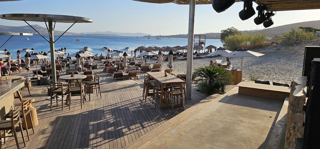 The sunbeds, umbrellas and shallow clear water of the beach club at the centre of Marcello beach on Paros