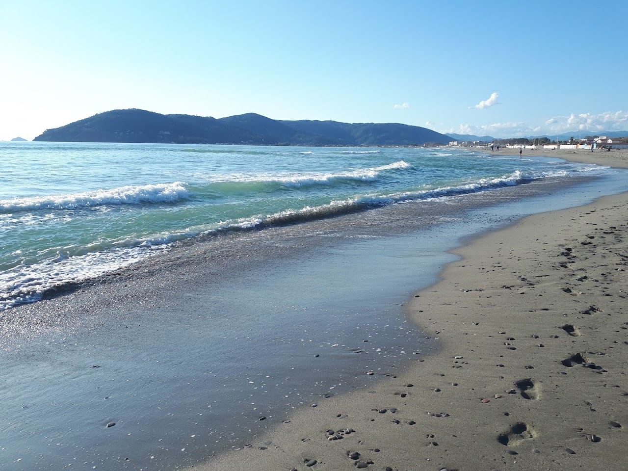Wide sandy beach at Marina di Carrara with the white Apuan Alps rising behind on the Tuscany coast
