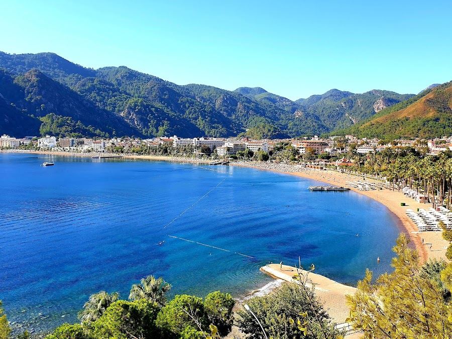 Long sweep of sunbeds and pine backed shore on the Icmeler beach near Marmaris