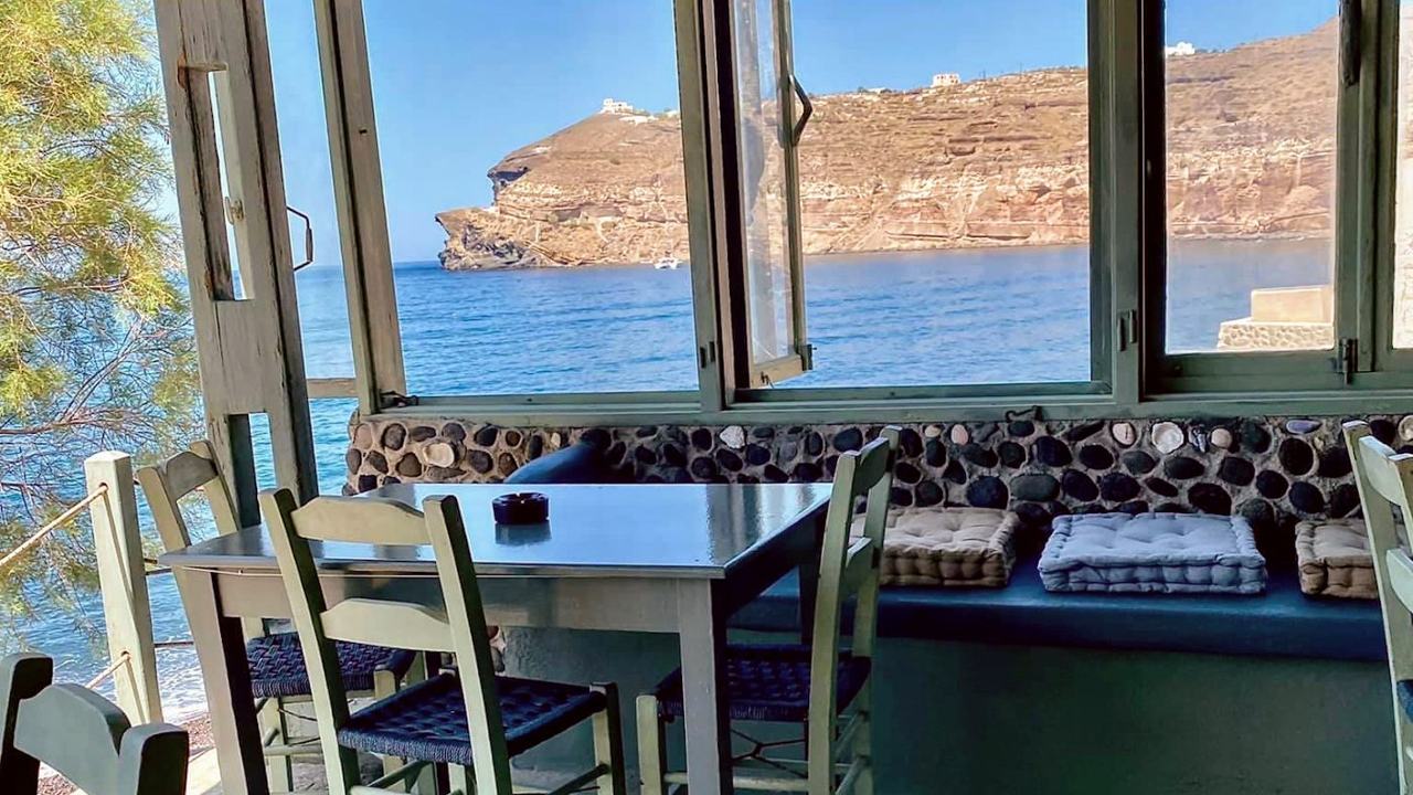 The black pebble cove of Mesa Pigadia sheltered by tall volcanic cliffs near Akrotiri in Santorini