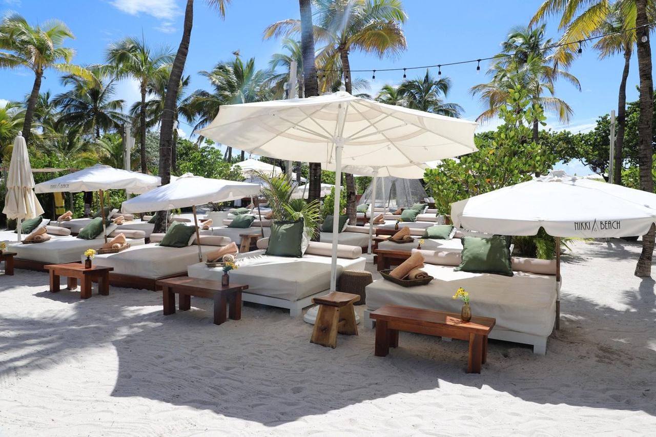 White daybeds and palms on the sand at a beach club at the southern end of South Beach in Miami Beach Florida
