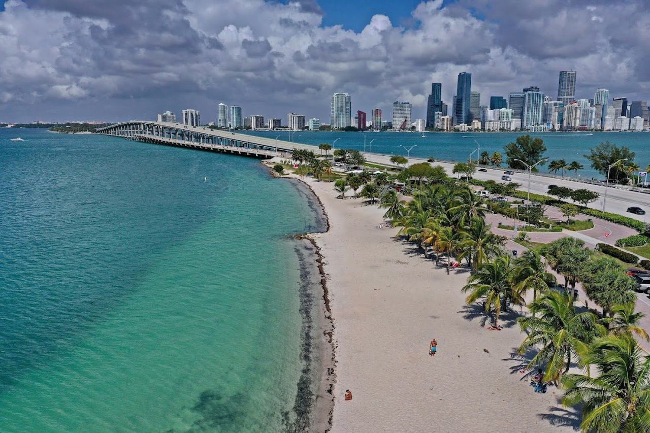 Windsurfers and calm shallow bay water at Hobie Beach along the Rickenbacker Causeway with the Miami skyline behind