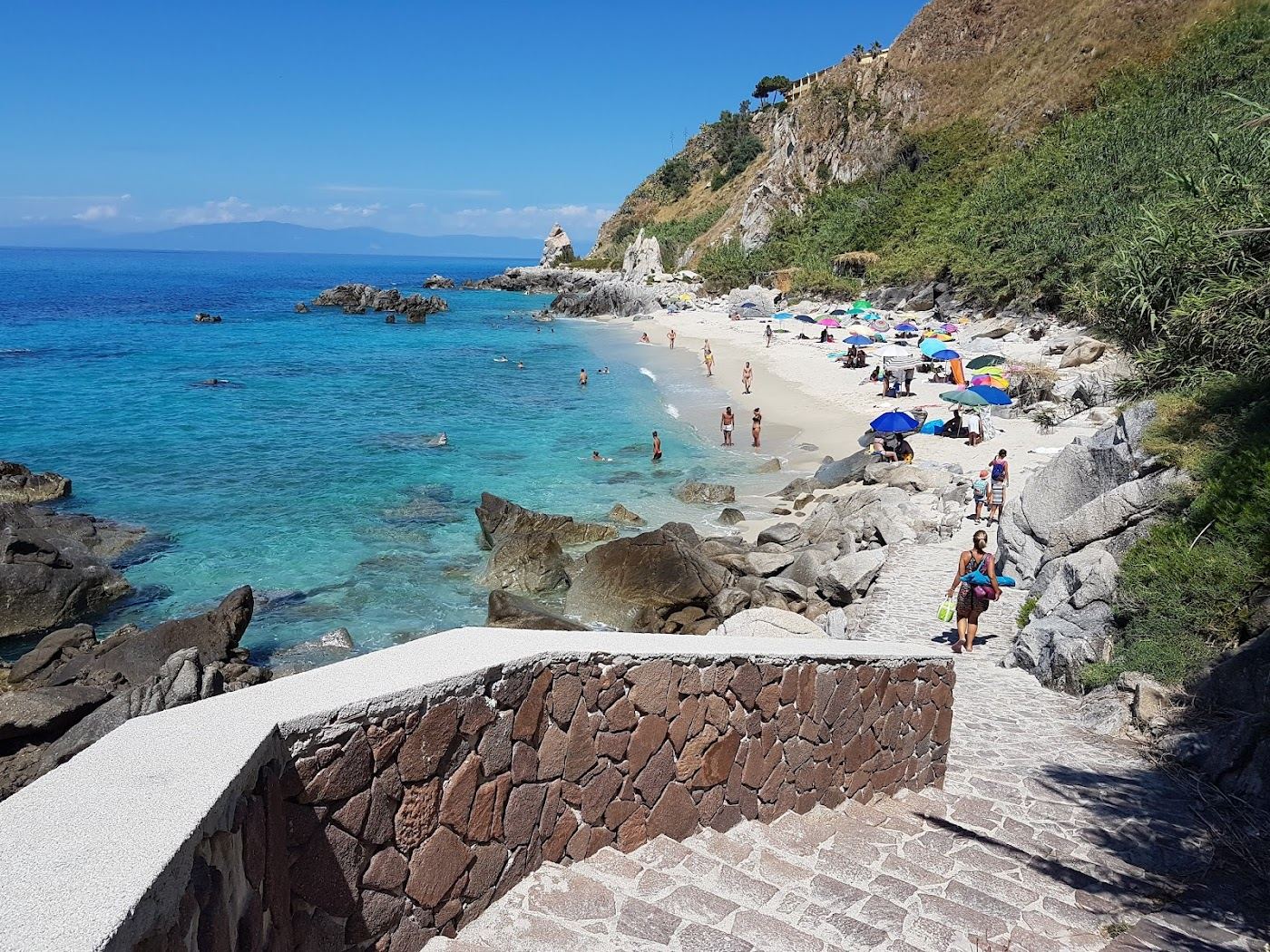 Clear water and pale sand below the cliffs at Michelino beach near Tropea Calabria